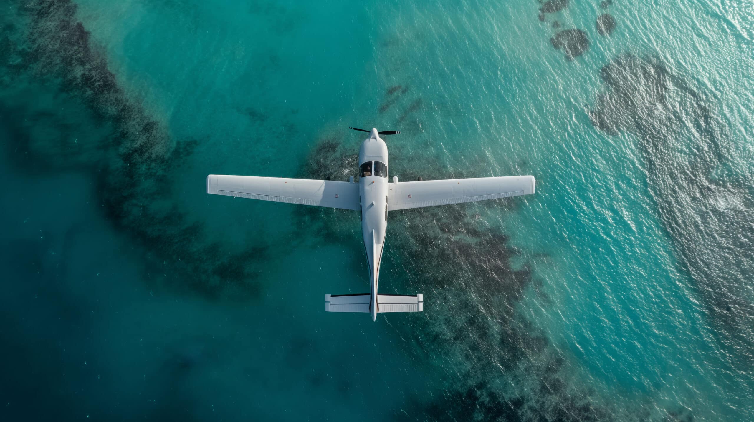 A small private plane is flying over the ocean shore. A single-engine plane flies low over the sea coast.