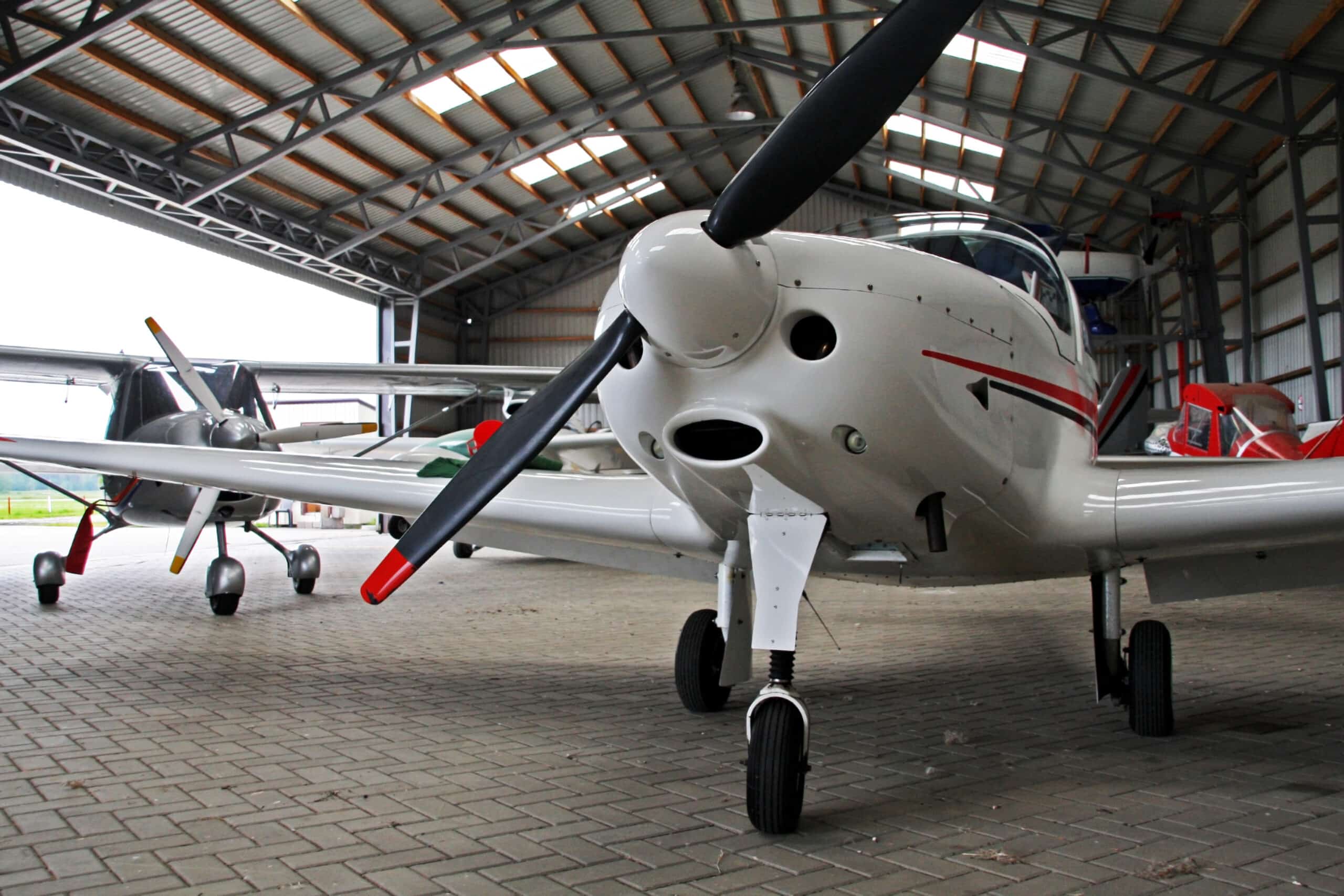 Small private lightweight propeller airplanes in hangar.