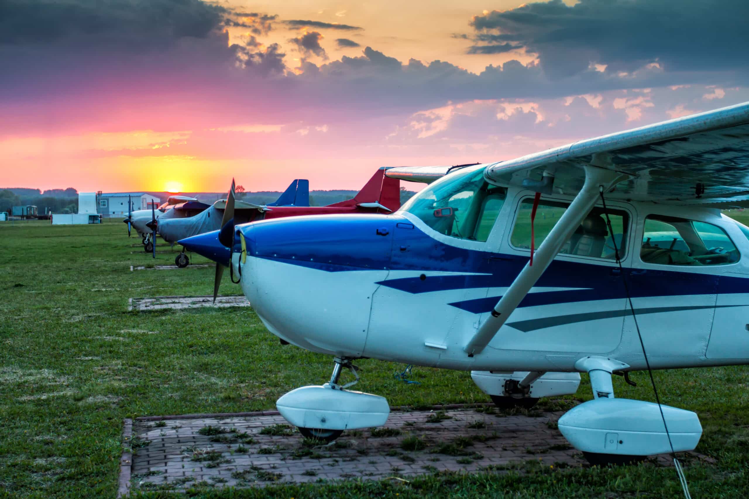 Small private aircrafts parked at the airfield at picturesque sunset